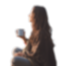 Woman sitting by the creekside with a warm drink in hand looking peaceful.