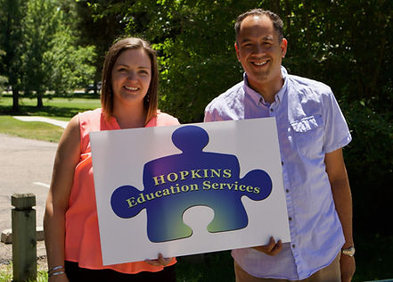 Founders Liz Hopkins and Corey Hopkins hold the Hopkins sign