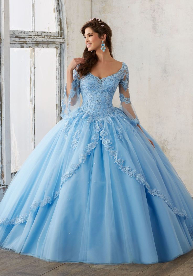 A Sweet 16 celebrant stuns in a sky blue ball gown with a twist, featuring unique details and modern touches. The dress combines classic elegance with a contemporary flair, perfect for a standout celebration.