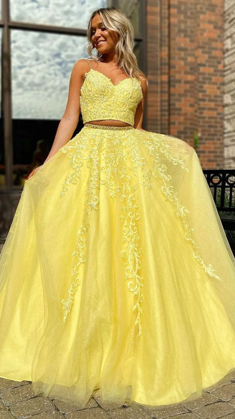 With blonde hair flowing, a Sweet 16 celebrant wears a lively yellow two-piece dress, posing against a brick wall with a window in the background. The bold color of the dress pops against the urban setting, adding a modern touch to her celebration look.