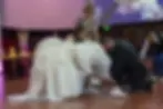 The 15th birthday celebrant, wearing a white dress, having her shoes changed by her father during the ceremony. Photo taken by a NYC Quinceañera photographer.