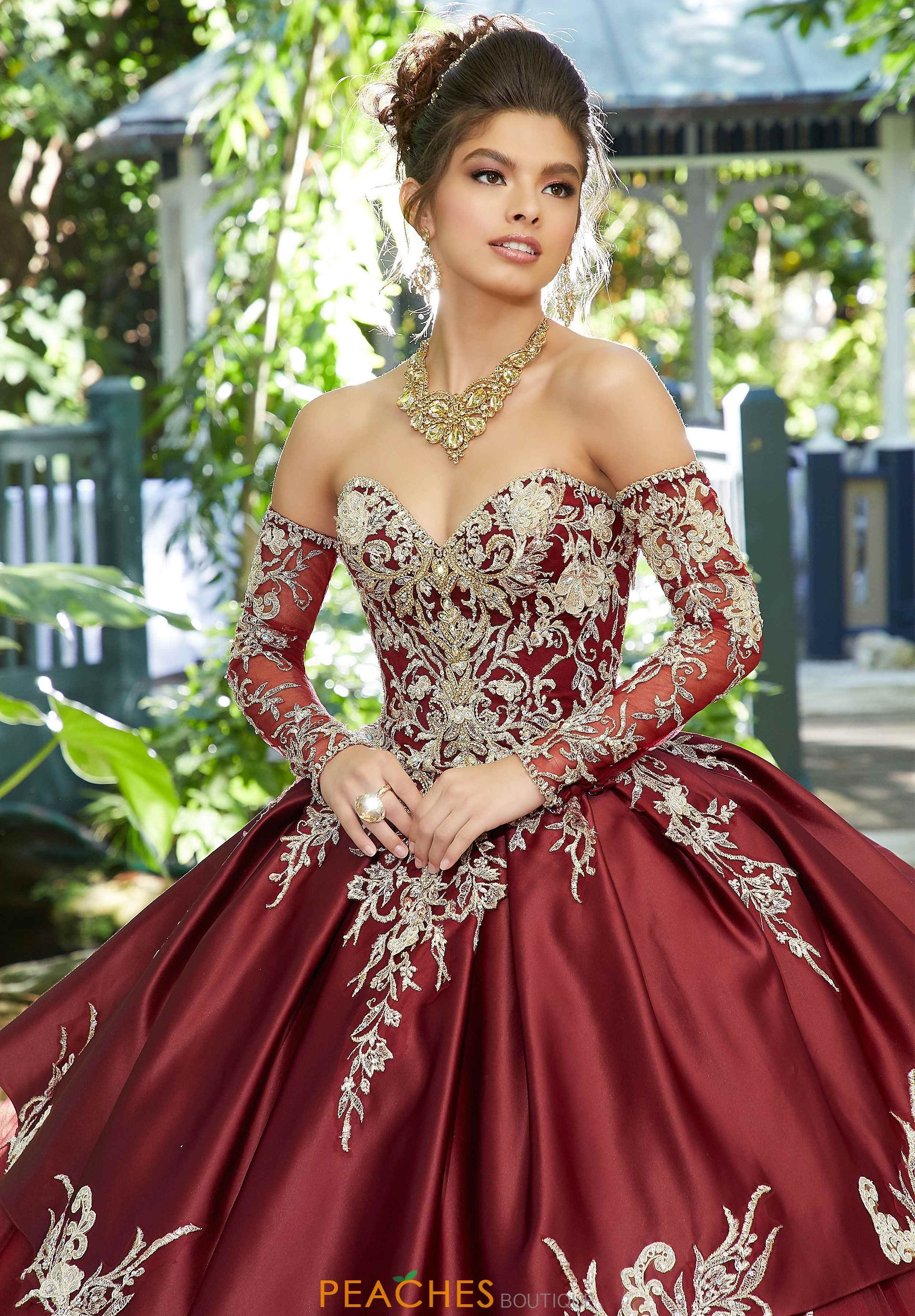 A quinceañera wearing a burgundy and gold dress, posing for a photograph during her photoshoot.