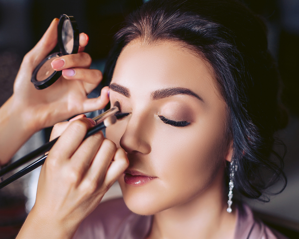 A makeup artist applies eyeshadow to a Sweet 16 celebrant. The room buzzes with excitement as final preparations are made for her big day.
