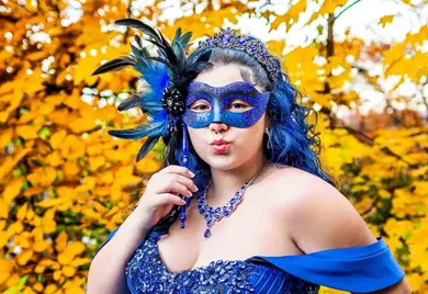 Sweet 16 celebrant wearing an elegant blue masquerade costume posing outdoors with vibrant autumn foliage during an NJ Sweet 16 photography session.