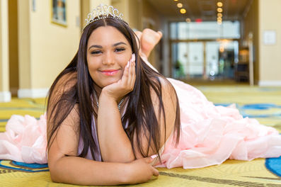 Wearing a pink dress, a Sweet Sixteen birthday celebrant poses for a photograph in a hotel in New York.