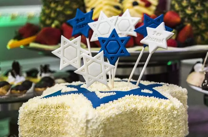 A white and blue Bar Mitzvah cake decorated with Star of David toppers. The cake features a vibrant, festive design, perfect for the celebration.