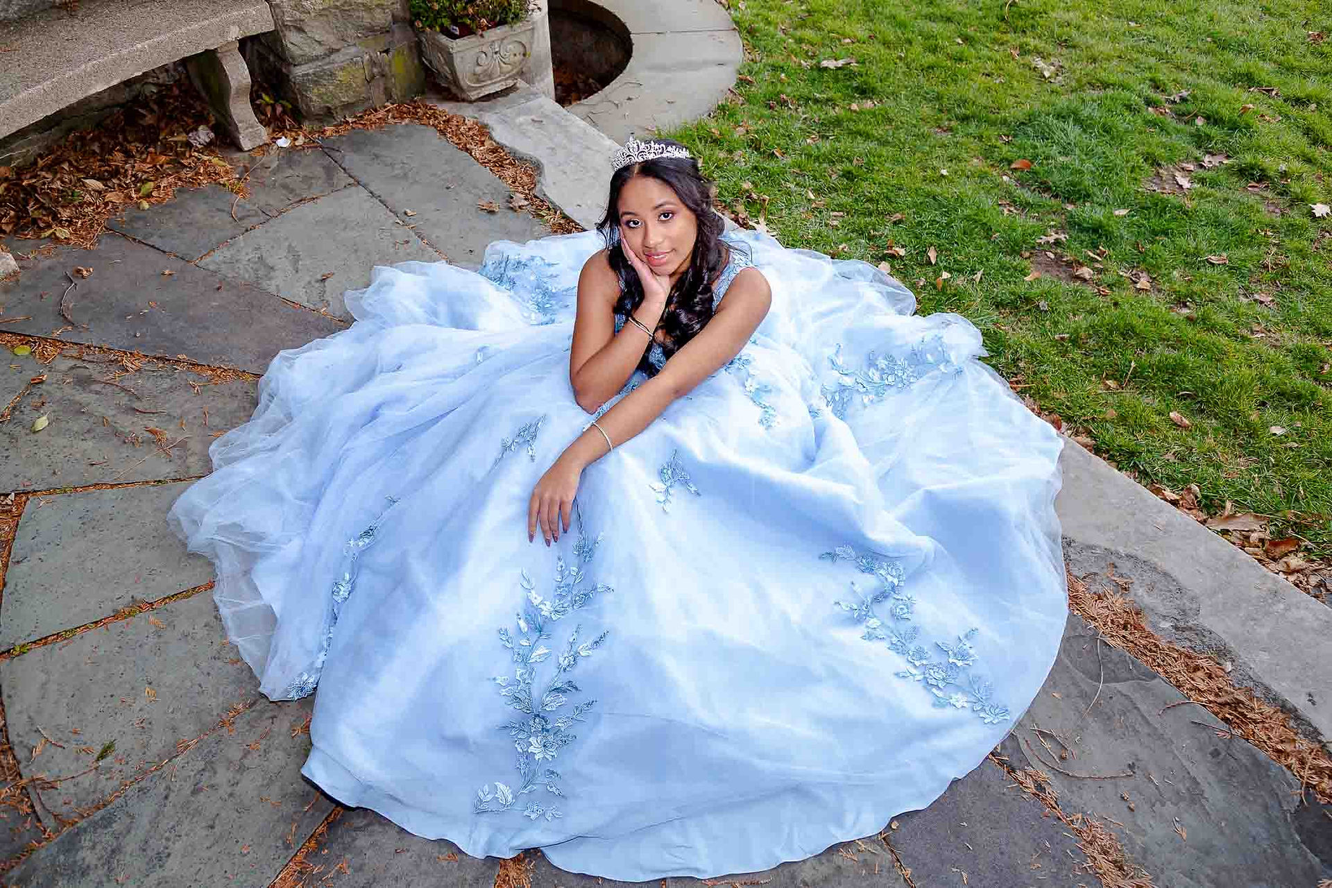 Sweet 16 birthday girl posing seated on the ground in a blue gown during her New Jersey photoshoot.