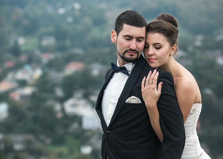 Wedding couple: bride lovingly embraces groom from behind.