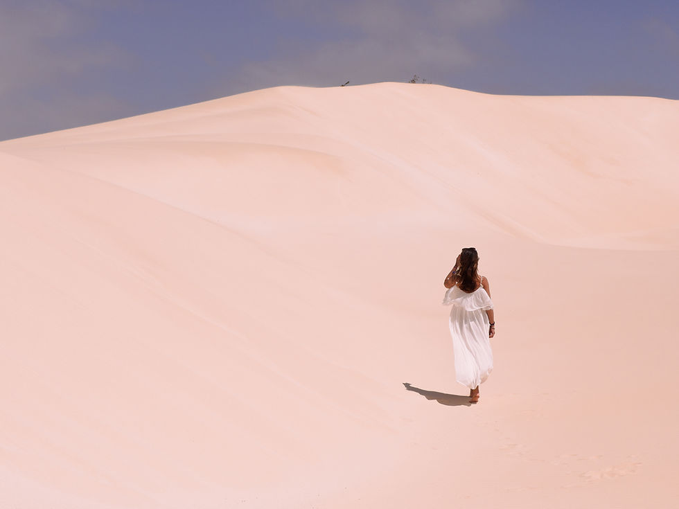 Femme en robe blanche marchant seule sur une dune de sable au Cap-Vert