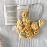 a crochet rose bag next to a book