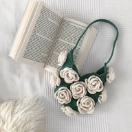 a crochet rose bag next to a book