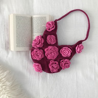 a crochet rose bag next to a book