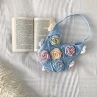 a crochet rose bag next to a book