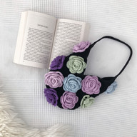 a crochet rose bag next to a book