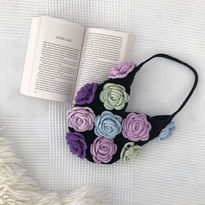 A black crochet bag with green, blue and purple roses