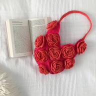 a crochet rose bag next to a book