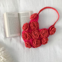 A pink crochet bag with orange roses