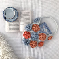 A white crochet bag with blue and orange roses