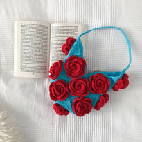 A blue crochet bag with red roses