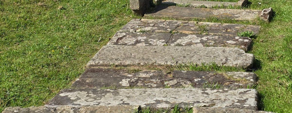 Flat stone grave markers in the grass at Whitby Abbey.