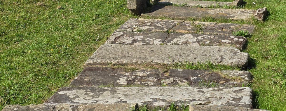 Flat stone grave markers in the grass at Whitby Abbey.