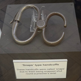 'Snaps' type handcuffs displayed on a museum plinth.