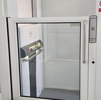 Wheelchair platform lift with glass door and control panel.