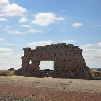 The 7m high wall that is still standing on the site of the Roman bath house. There is an open archway in the middle where a door would have once stood.