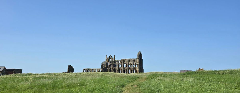 Path leading to Whitby Abbey ruins under a clear blue sky.