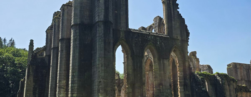 Stone ruins of Fountains Abbey against a blue sky