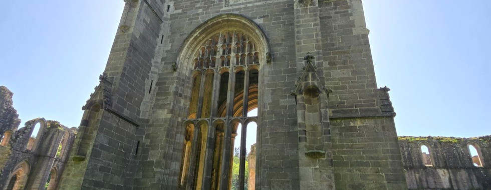 The tall stone tower of Fountains Abbey ruins.