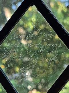 Tudor graffiti in the form of cursive writing etched into a leaded glass window at Speke Hall.