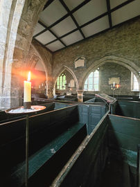 The box pews of the church. In the image you can see the the candles around the church used to light it due to the lack of electricity.