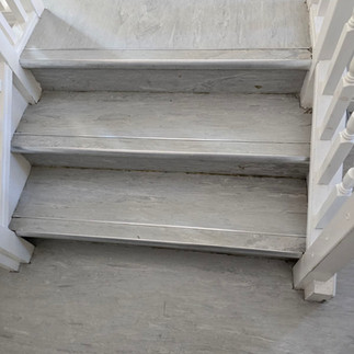 Three grey wood-effect stairs with white railings.