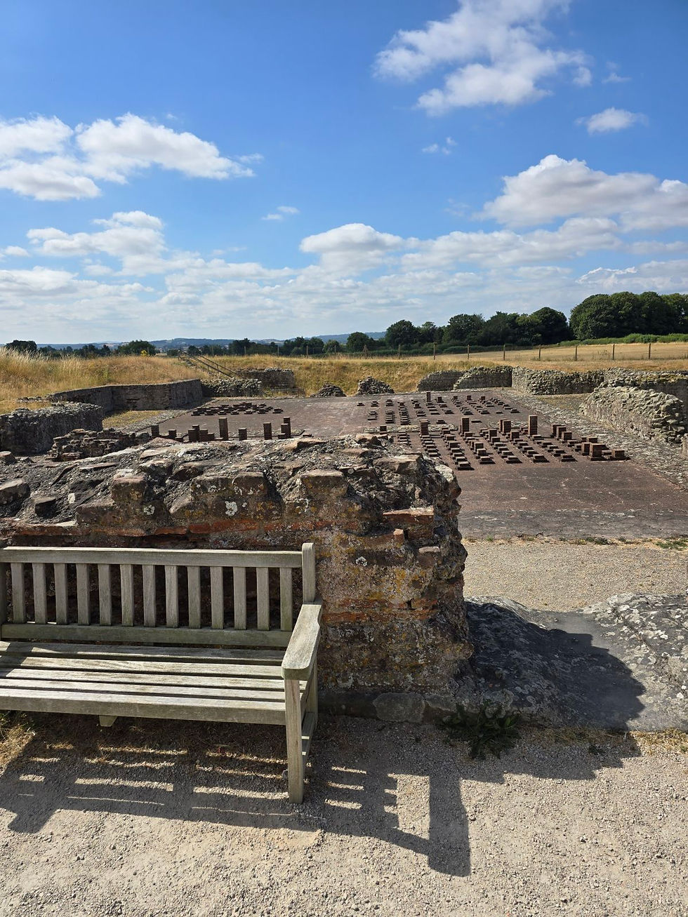 A bench that is not in the shade on site next to the ruins.