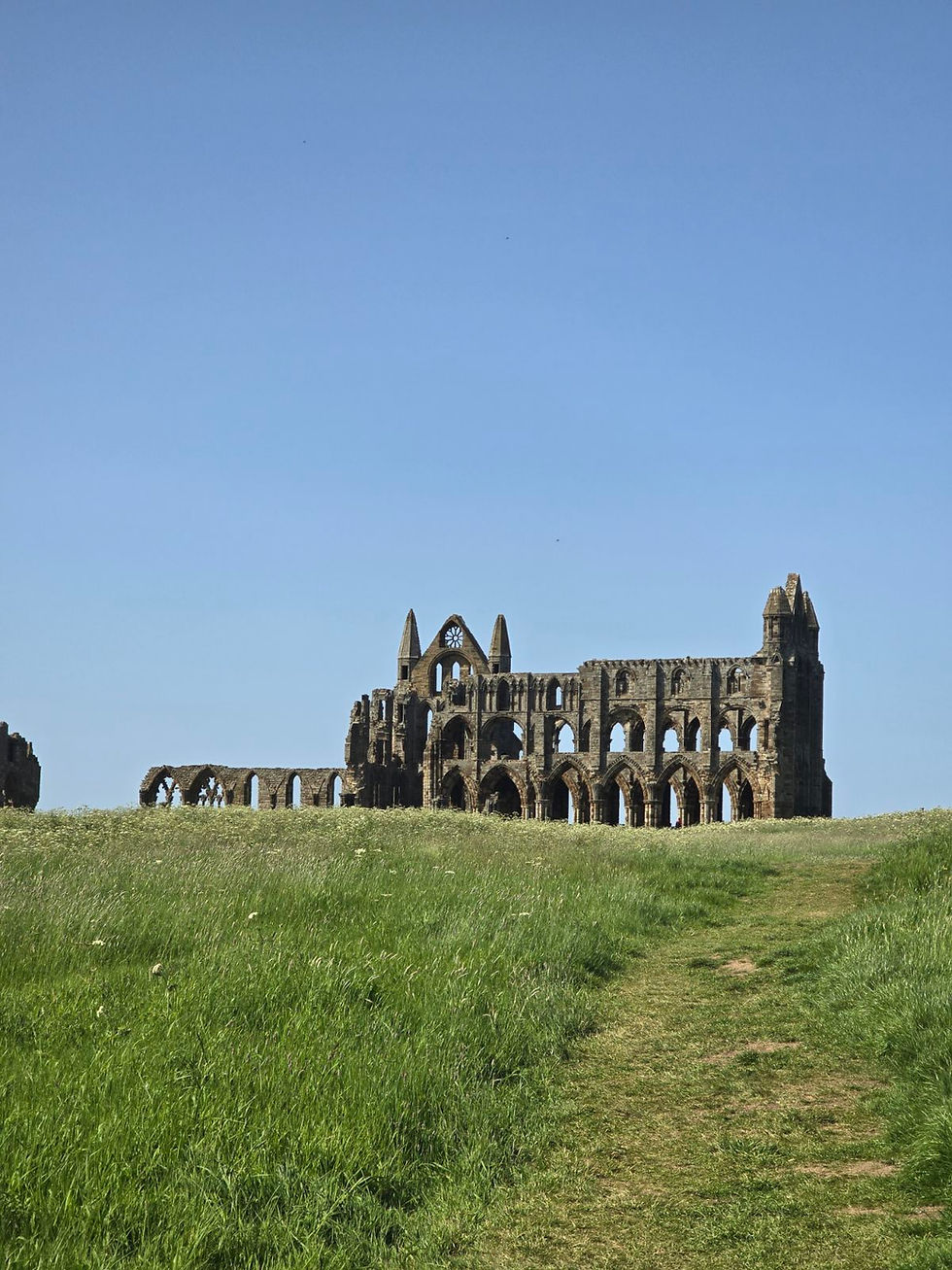The ruins of Whitby abbey. The sky is blue with no clouds.