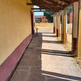 A covered porch-like section, of the reconstructed Roman villa on site. The yellow walls and columns are clearly visible.