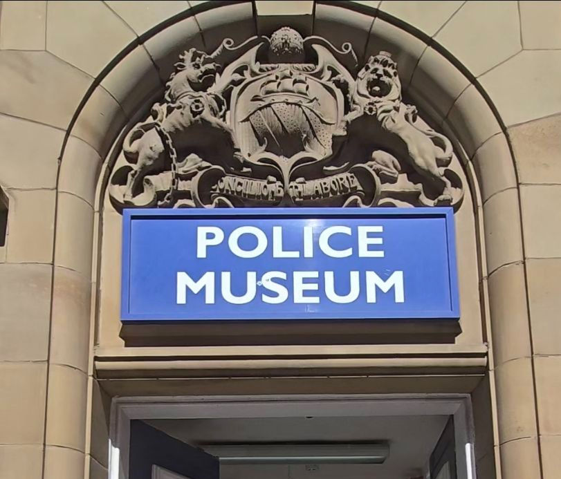 A blue sign that says Police Museum on a stone entrance.