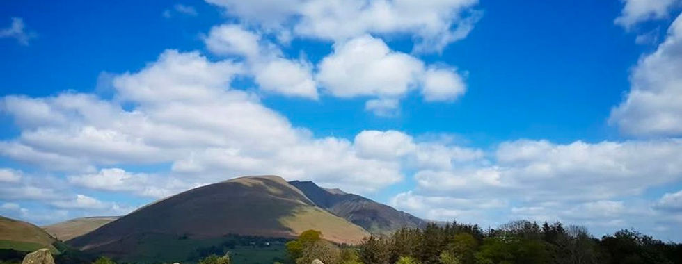 Castlerigg Stone Circle with mountains and blue sky.