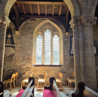 Stone arches, pews, and lancet window in the Church.
