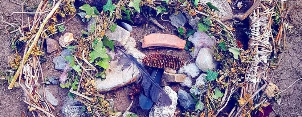Small ritual circle of stones, twigs, and flowers.