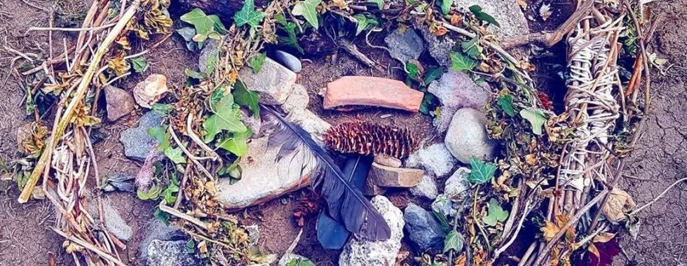 Small ritual circle of stones, twigs, and flowers.