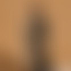 Modelo usando um trench coat verde militar de algodão com amarração na cintura e detalhes de botões duplos, em um cenário de parede texturizada em tom terroso.