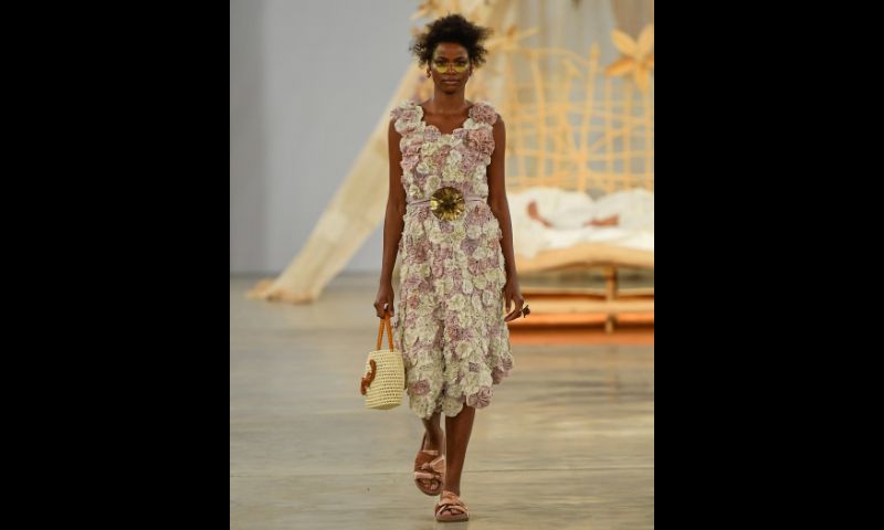 Modelo desfila usando vestido de crochê nos tons branco e lilás/rosa claro