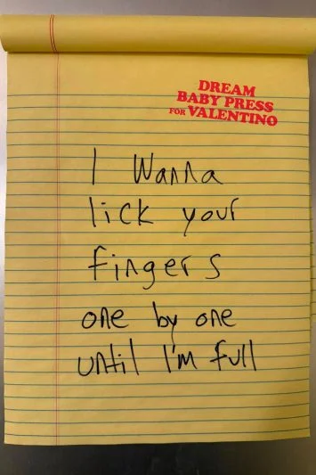 Um bloco de notas amarelo com um bilhete escrito à mão: "I wanna lick your fingers one by one until I’m full." O logo Dream Baby Press for Valentino aparece no topo da página.