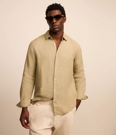 Modelo vestindo camisa de linho bege e calça off-white, usando óculos escuros. Um visual elegante e casual que remete ao stealth wealth.