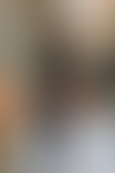 Modelo desfilando em um look composto por casaco militar verde com detalhes de pele marrom, top preto de renda, shorts de couro preto, botas de cano alto e meias até a coxa, segurando uma clutch de pele marrom.