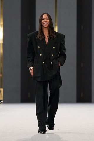 Olivier Rousteing na passarela ao final do desfile, vestindo um terno preto oversized de risca de giz, com abotoamento duplo e ombreiras estruturadas.
