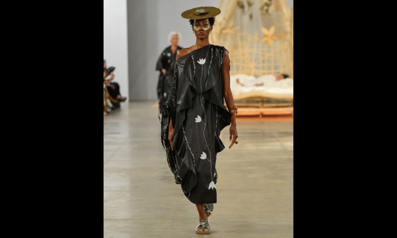 Modelo desfila com vestido preto, de estampa floral branca.