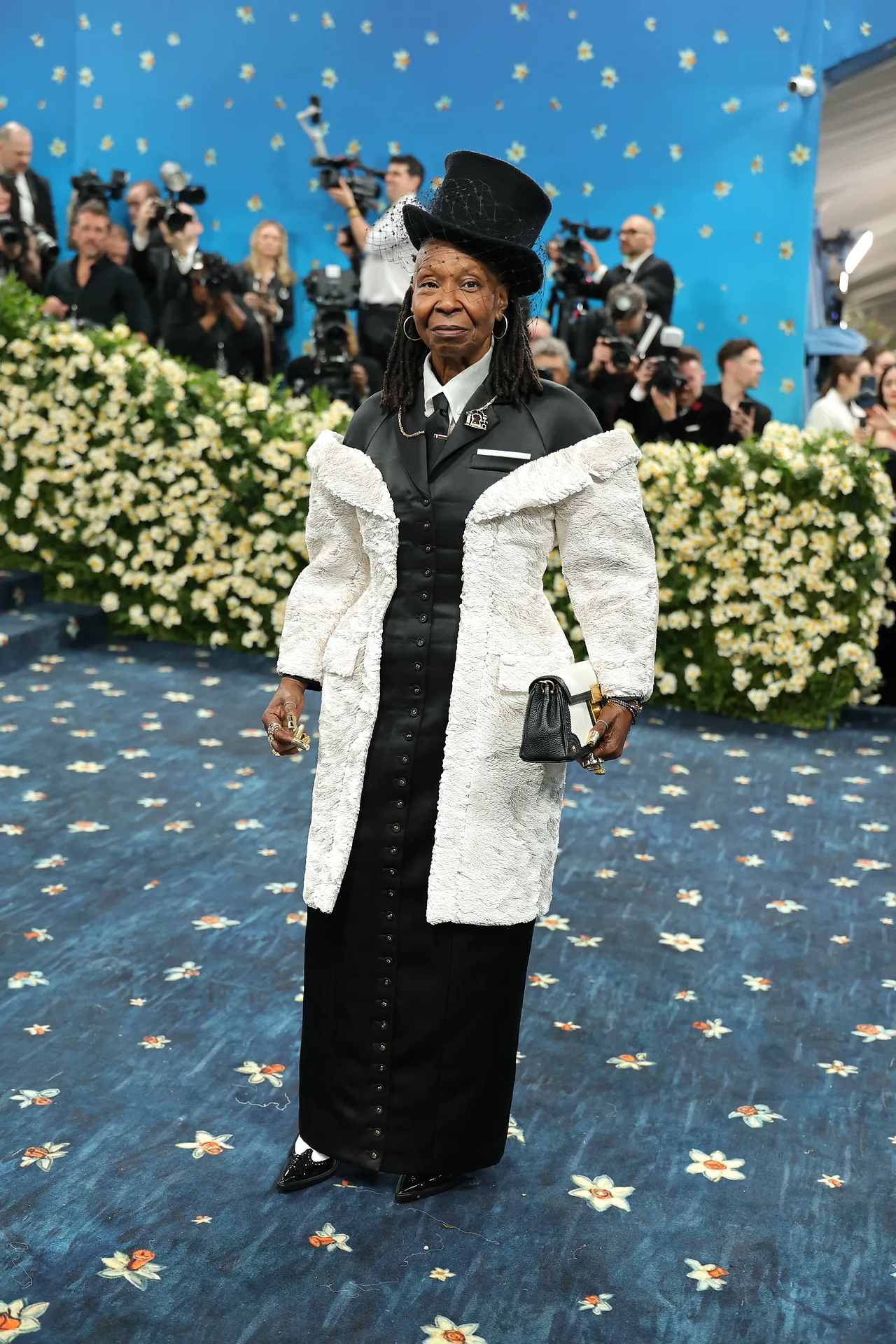 Whoppi Goldberg do Met Gala 2025 mistura texturas em preto e branco com boina estilizada, interpretando a alfaiataria negra com ousadia.